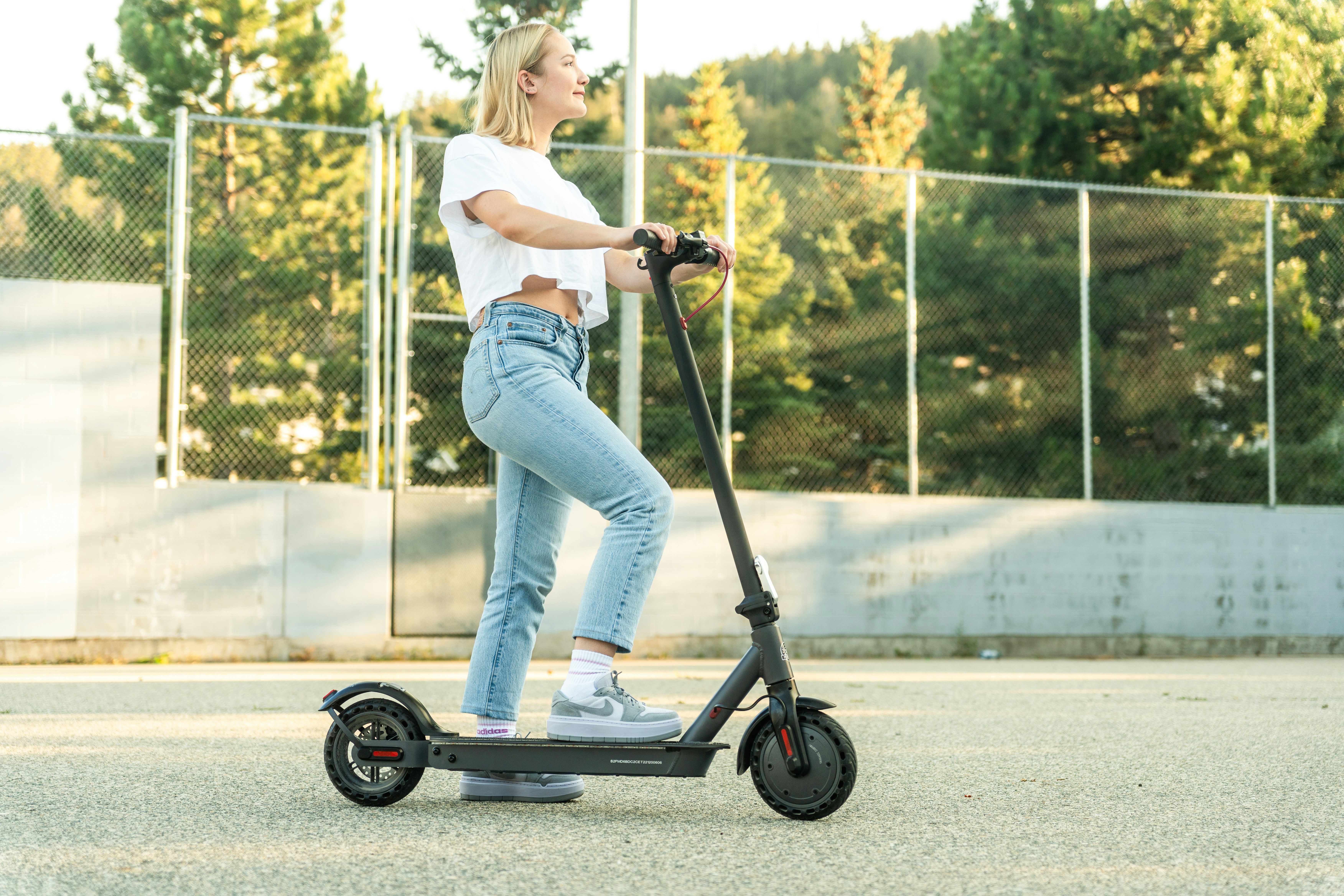 Kvinna som står med ena foten på en elscooter